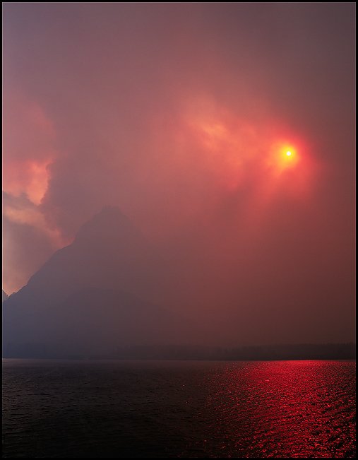 Grinnell Point covered in smoke with vibrant bright red sunlight from the Trapper Creek Forest fire, Glacier National Park, Montana, July